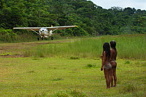 Huaorani Indians waiting for light aircraft coming into the Huaorani Indian community. Bameno Community, Yasuni National Park, Ecuador, May 2007. Model release B#10.