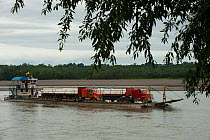 Oil barge transporting trucks on the Napo River. Yasuni National Park, Amazon Rainforest Ecuador.