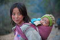 Monpa child carrying a baby in sling on her back, between Dirang and Mandala, Arunachal Pradesh, India, February 2011.