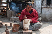 Monpa man with typical head dress made from Yak hair carving a mask. Shurbi village, near Tawang, Arunachal Pradesh, India, February 2011.