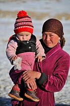 Portrait of a Kyrgyz shepherd with her child. Naryn National Park, Kyrgyzstan, Central Asia, November 2009.