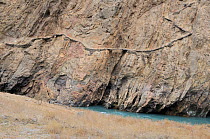 A path traversing a steep ravine above a mountain river. Naryn National Park, Kyrgyzstan, Central Asia, November.