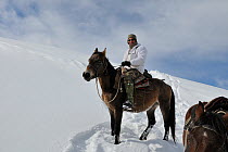 Photographer Eric Dragesco mounted on horse  in snow, on an expedition to find Tien Shan Argali (Ovis ammon karelini). Naryn National Park, Kyrgyzstan, Central Asia, November.