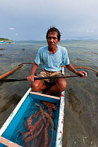 Hook and line fisherman with his day's catch of a dozen live Coral trout (Plectropomus leopardus) to sell to a Live Reef Fish grower, Palawan, Philippines, May 2009.
