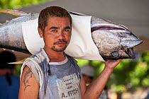 Dock worker carries tuna to the fish landing and processing area of the Docks, Sarangani, Philippines, April 2010 . . NOT AVAILABLE FOR MAGAZINE USE IN GERMAN-SPEAKING COUNTRIES UNTIL 1ST JULY 2013.
