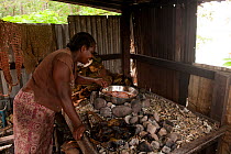 Rinda Melsen cooks crispy sweet potatoes and yam cooked with hot stones in a traditional motu stone oven. Onma Lodge, Kolombangara, Western Province, Solomon Islands, July 2010.