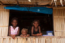 Three young Melanesian girls looking out from their kitchen window, Kolombangara, Western Province, Solomon Islands, July 2010.