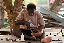 Carver Huimes Namusu carves out a groove from the rim of a coconut wood bowl to make space for the nautilus mother of pearl inlay, Chea Village, Marovo Lagoon, Solomon Islands, Melanesia, Pacific, Jul...