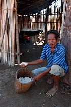 Timorese man with salt for sale, made by boiling brine in open pan for 8hrs over fire of palm fronds, East Timor, August 2010.