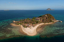 Aerial view of a private tropical island surrounded by a white sandy beach and coral reefs. note helipad at end of pier at top left of the island, Palawan, Philippines, April 2010.