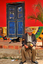 An old man and a dog sitting on the street in the colourful city of Roquira ('City of Pots'). Boyaca department, Colombia, February 2011.