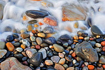 Sea surf washing over colourful water-smoothed pebbles, Normandy, France, October 2010.