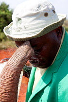 Orphan baby elephant (Loxodonta africana) explores keeper's face with its trunk, David Sheldrick Wildlife Trust Nairobi Elephant Nursery, Kenya, July 2010.