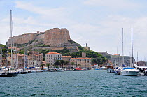 Sailing yachts moored in Bonifacio harbour overlooked by the Bastion de l'Etendard fortress and the citadel. Southern tip of Corsica, France, May 2010.