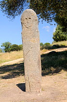 Tall Bronze age granite statue menhir standing stone carved c 3,500 years ago at Filitosa with carved face and trace of a sword. Corsica, France, June 2010.
