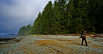 A man hiking along a forested stoney beach. Pacific Rim National Park, Vancouver Island, Canada, Septemner 2010.