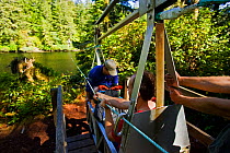 People preparing to cross a river in a cable-car-like chair bridge. The West Coast Trail, Pacific Rim National Park, Vancouver Island, Canada, September 2010.