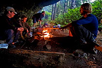 Hikers building up a fire in their cliff-overhang cave. The West Coast Trail, Pacific Rim National Park, Vancouver Island, Canada, September, Model released