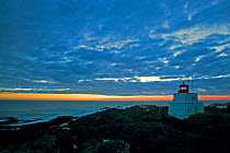 Dawn light breaking through clouds behind a lighthouse. Amphitrite Point, Ucluelet, Vancouver Island, Canada, October 2010.