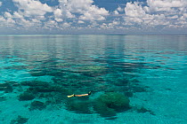 Flat calm seas of Tubbataha Reef, with a snorkeler swimming at the surface. Tubbataha National Marine Park, Philippines, April 2009.