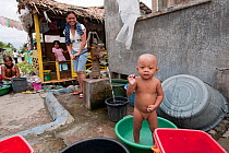 A Filipino toddler taking a bath by the community water pump. Donsol, Phillipines, June 2009.