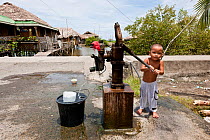 A Filipino toddler pumping water out of the community water pump for his bath. Donsol, Philippines, June 2009.