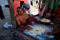 Man making patties of Cassava. The tuber is grated and serves as food staple, more common than rice for remote Indonesians. Runduma Island, Sulawesi, Indonesia, November 2009