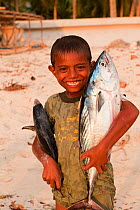 Young Indonesian boy posing with two freshly-caught fish. Kei Islands, Moluccas, Indonesia, November 2009.