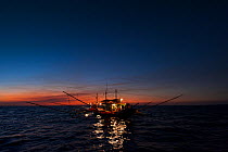 A fishing boat using a kerosine lamp to illuminate the sea from dusk to dawn. The light attracts the fishermen's target fish, anchovies and silversides. Philippines, March 2010.