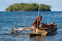Old man of the of M'buke community gathering firewood for his home in a small traditional outrigger canoe. New Ireland, Papua New Guinea, June 2010.