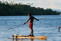 Man spear fishing from his dugout canoe. This is a Marine Protected Area managed by the local community, and fish are abundant. M'buke Island, New Ireland, Papua New Guinea, June 2010