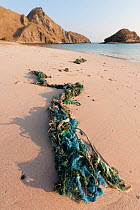 Discarded ropes and fishing tackle strewn along the shoreline on a beach, Komodo island, Indonesia, August 2009.