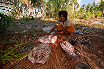 Fisherman cutting and salting his catch of fish to preserve fish for journey back to Runduma from Anano Island, Indonesia, November 2009.