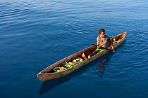 Papua New Guinean islander paddling his dugout canoe to trade fresh vegetables. He will come back with instant noodles, rice, soap and other groceries he would normally have no access to. Papua New Gu...