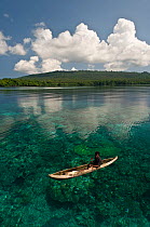 Papua New Guinean islander paddling his dugout canoe to trade fresh vegetables. He will come back with instant noodles, rice, soap and other groceries he would normally have no access to. Papua New Gu...