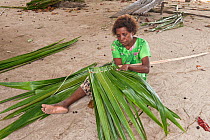 Woman from Enuk Island making her thatched roof. Kavieng, Papua New Guinea, June 2010.