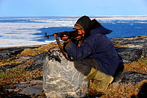 Inuit hunter aiming his gun in an icepack landscape. Igloolik, Foxe Basin, Nunavut, Canada, July 2011.