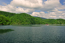 A pleasure boat and the wooded hills by a lake. Plitvice National Park, Croatia, May.