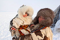 At their winter camp, Emma Vanuito, a Nenets woman, holds her daughter, Nenya. Tambey. Yamal Peninsula, Western Siberia, Russia. March 2011