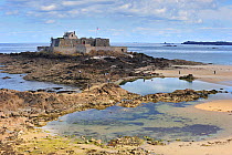 Fort National and tourists walking on beach at low tide at Saint-Malo, Brittany, France. September 2010.