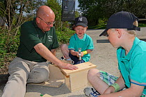 Osprey Project Information Officer, Paul Stammers, building bird boxes with children during an event at the Lyndon Visitor Centre, Rutland Water, Rutland, UK, April 2011