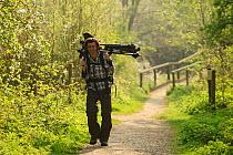 Cameraman, Will Bolton, carrying photographic equipment on location for 2020 Vision at Rutland Water, Rutland, UK, April 2011, Model released