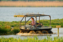 Assistant Warden Lloyd Park checks nesting islands and rafts at the Anglian Birdwatching Centre using an amphibious vehicle, Rutland Water, Rutland, UK, April 2011, Model released