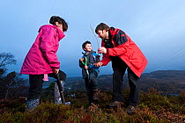 Children from Lochinver primary school being shown how to plant trees on moorland at Culag Wood, Sutherland, Highlands, Scotland, UK, January 2011. Did you know? One tree can remove up to one tonne of...
