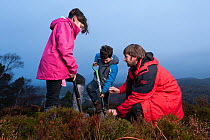Children from Lochinver primary school being shown how to plant trees on moorland at Culag Wood, Sutherland, Highlands, Scotland, UK, January 2011