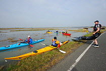Carrying kayaks across Wallasea Causeway at high tide during a Kayak event to canoe around Wallasea Island organised by the RSPB and Burnham-on-Sea Yacht Club. Essex, UK, January 2011