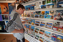 Young man looking at cards inside the Scottish Seabird Centre in North Berwick showing economic benefits of presence of Bass Rock, Firth of Forth, Scotland, UK, July 2010