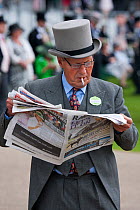 A punter dressed in top hat and tail, looks at the Racing Post, in the Royal Enclosure, in June 2011, on the 300th Anniversary of Royal Ascot, Berkshire, England. (not released)
