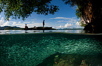 Schooling Silverside fish (Antherinidae) split level with karst limestone walls, West Papuan fisherman in boat, North Raja Ampat, West Papua, Indonesia, February 2002.
