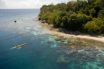 Aerial view of kayaker crossing translucent water above coral reef, Solomon Islands, Melanesia, August 2008.